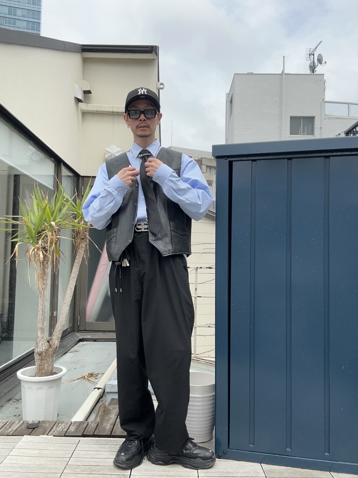 シャツとベスト、キャップを合わせた東龍治の全身写真